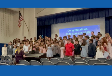 photo of 6th graders in gym/stage performing a song at Promotion